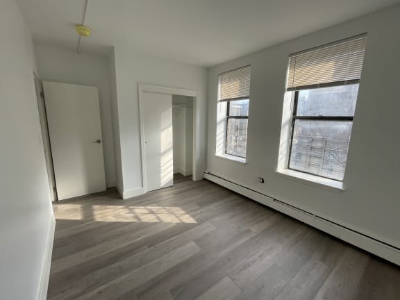 an empty bedroom with three windows and a door