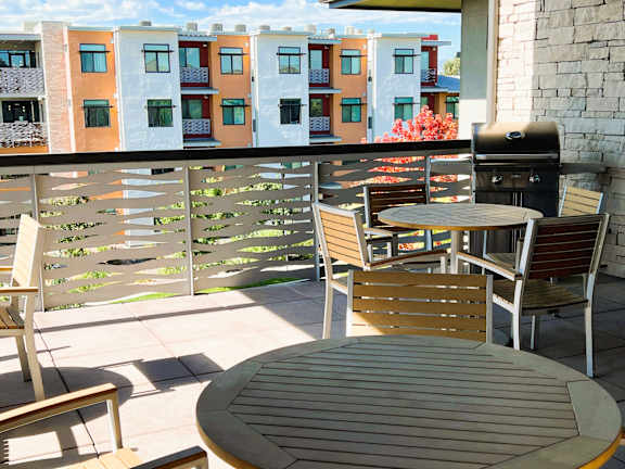 A patio with a table and chairs and a grill.