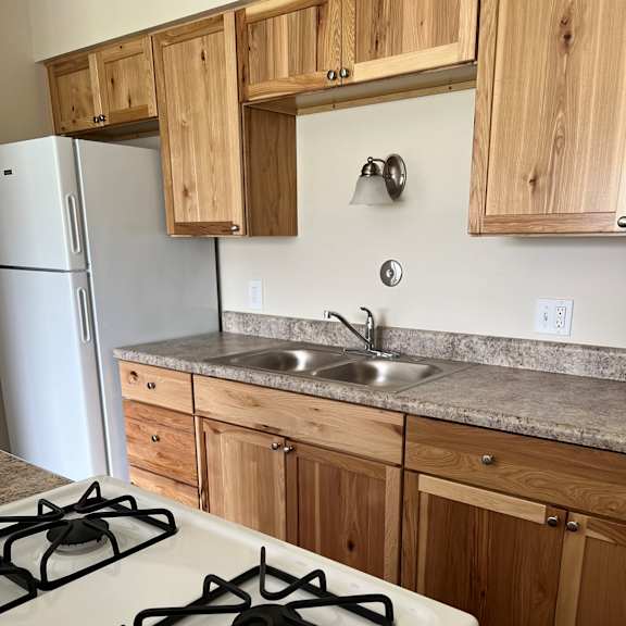 a kitchen with a stove and wooden cabinets