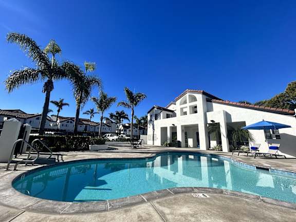 a swimming pool with palm trees in front of a hotel