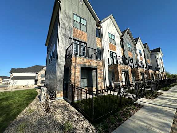 an exterior view of a row of apartments with a sidewalk and grass at The BLVD at Wilson Crossings in Wyoming, MI 49418