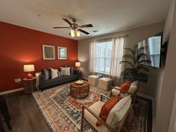 a living room with red walls and a ceiling fan at Watermark at Steele Crossing, Arkansas