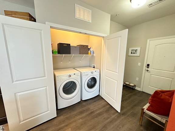 a laundry room with a washer and dryer and a shelf over the door at Watermark at Steele Crossing, Fayetteville, AR