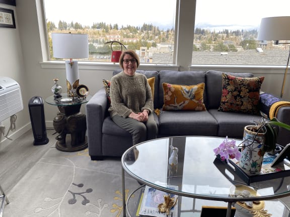 a woman sitting on a couch in a living room at Harbor Heights 55+ Community, Olympia, 98501