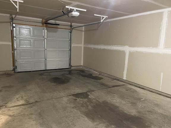 A garage with a white door and a concrete floor.