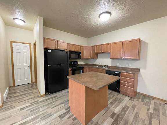 A kitchen with black appliances and wooden cabinets.