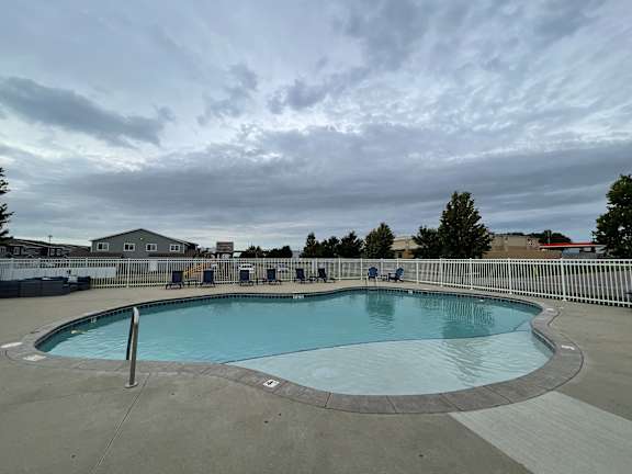 A large outdoor swimming pool with a metal fence around it.
