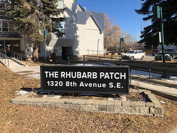 A sign that says "The Rhubarb Patch" is in front of a building.