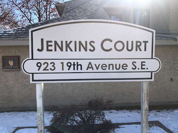 A street sign for Jenkins Court stands in front of a house.