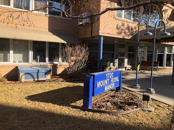 A sign that says 1720 Mount Royal Manor stands in front of a building.