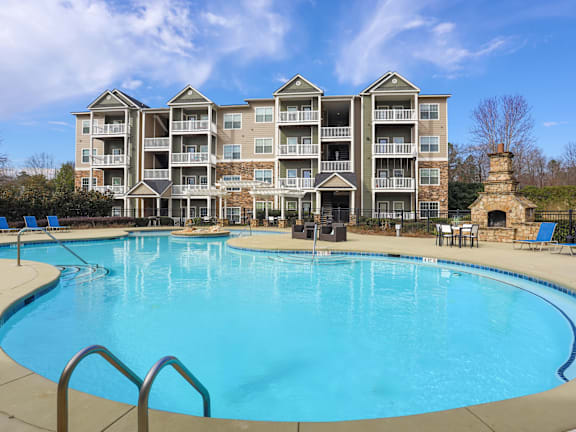 A large swimming pool in front of a multi-story apartment building.