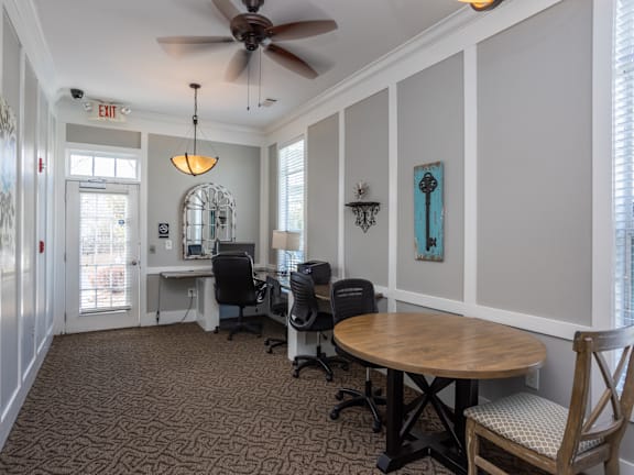 A room with a table, chairs, and a ceiling fan.
