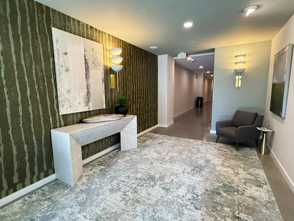 A hallway with a bench, a chair, and two paintings on the wall.