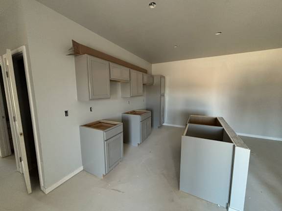A room with white cabinets and a door open to another room.
