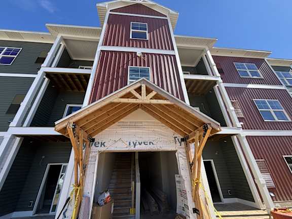 A multi-story building with a red and white striped facade is under construction.