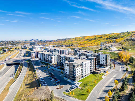 A large apartment complex is surrounded by a highway and trees.