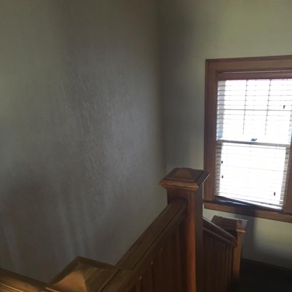 A room with a window and a wooden staircase.