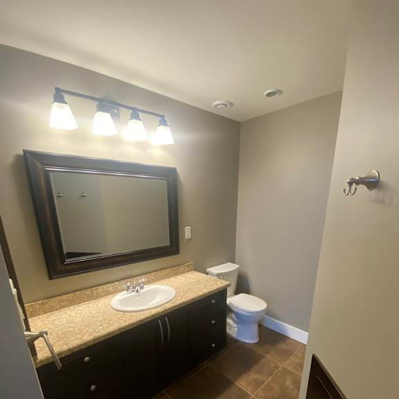 A bathroom with a mirror, light fixture, and a toilet.