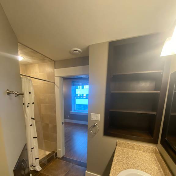 A bathroom with a sink, mirror and shower.