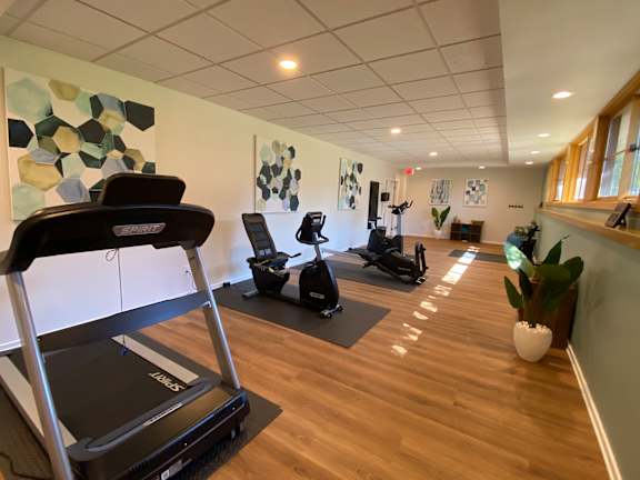 A treadmill is in the foreground of a well-equipped gym.