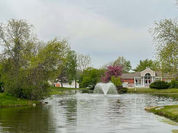 a fountain in a pond with a house in the background