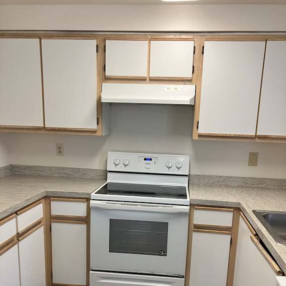 A kitchen with white appliances and wooden cabinets.