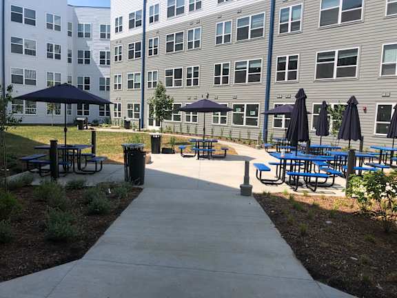 a patio with tables and umbrellas in front of a building