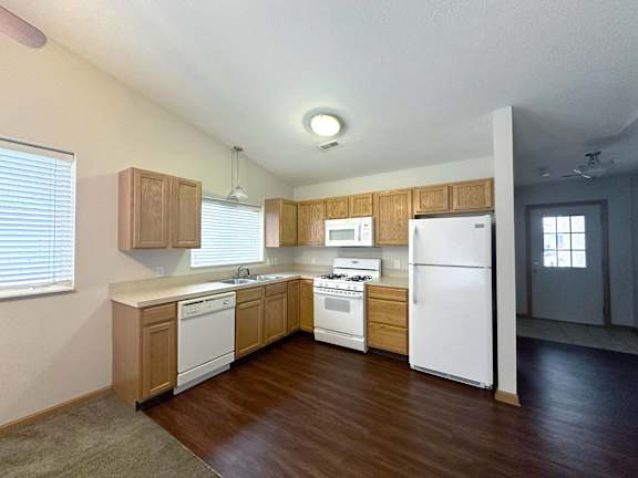 A kitchen with white appliances and wooden cabinets.