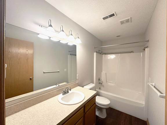 A bathroom with a sink, mirror, toilet and bathtub.