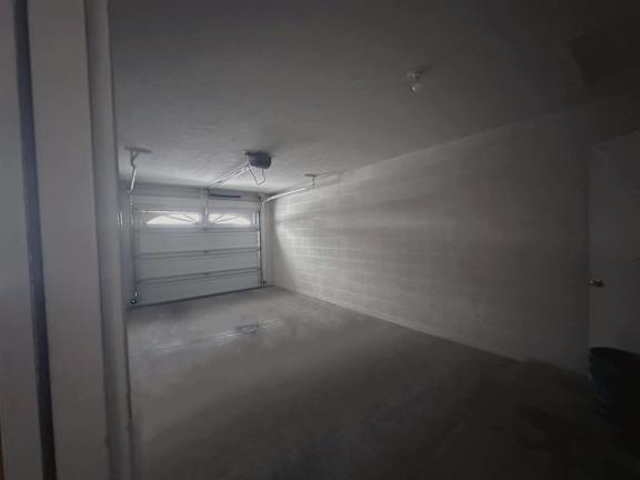 A room with a white wall and a window on the left side.