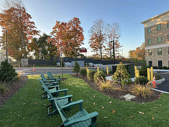 a row of green park benches in front of a building