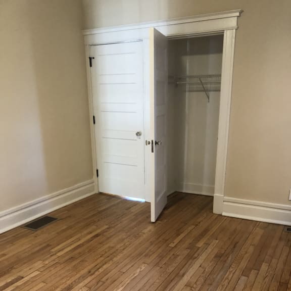a small closet with a wooden floor and a white cabinet