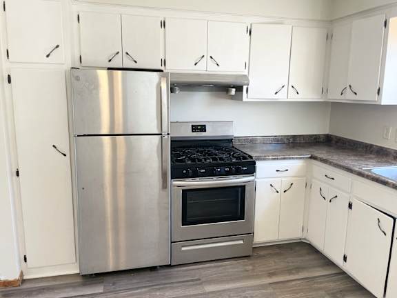 A kitchen with a stainless steel refrigerator, oven, and cabinets.