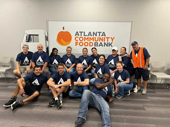 A group of people in blue shirts are posing for a photo in front of a sign that says "Atlanta Community Food Bank".