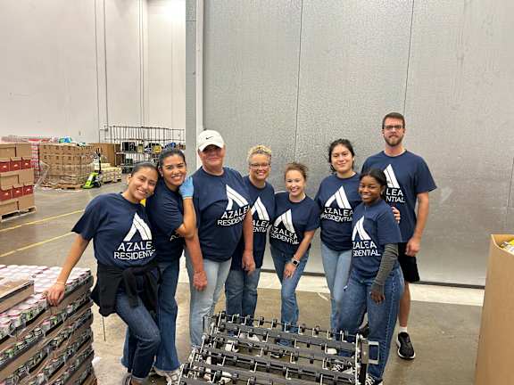 A group of people in blue shirts with the word "Residential" on them are standing in a warehouse.