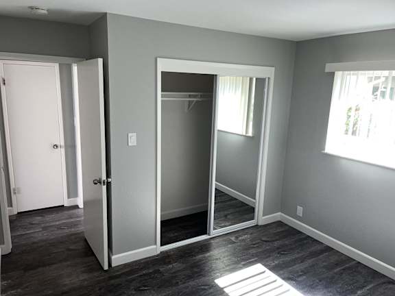 a bedroom with a mirrored closet and a window