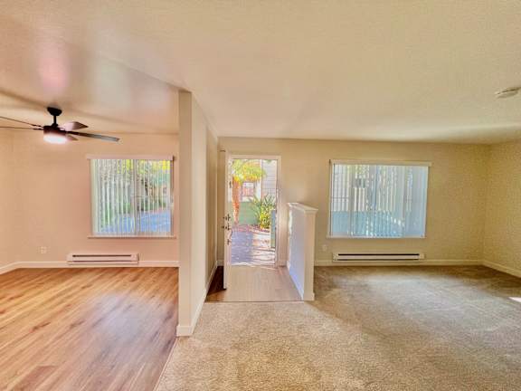 A room with a ceiling fan and two windows.