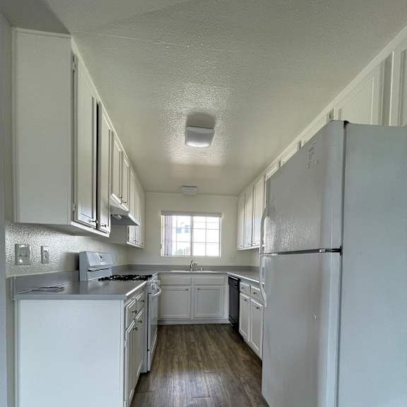 A kitchen with white appliances and wooden walls at Lido Apartments, California