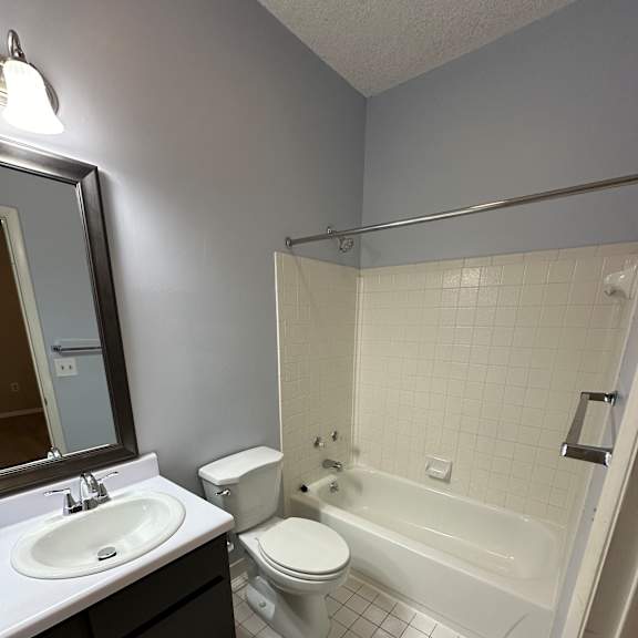 A white toilet is in a bathroom with a white tiled shower.