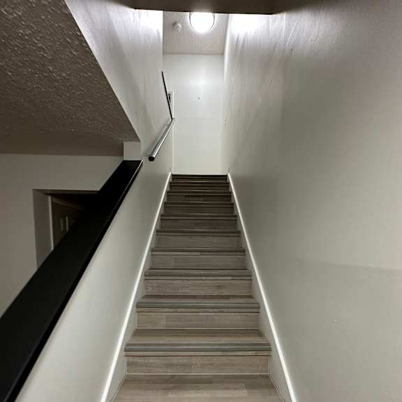A long hallway with a white ceiling and a wall with wood paneling.