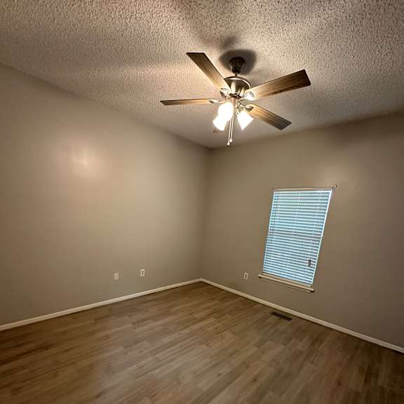 A ceiling fan is mounted on a wall in a room with wooden flooring.