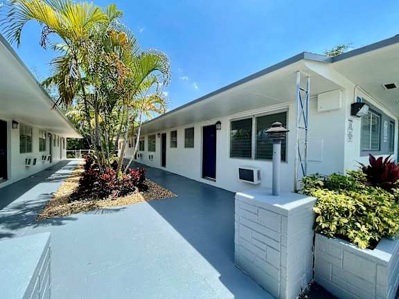 a long white building with a palm tree in front of it at Lakeside @ Biscayne Gardens,North Miami, FL,33181