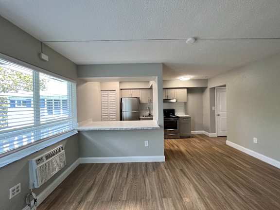 an empty living room and kitchen with a large window  at Palm Gardens @ Biscayne Gardens, North Miami, FL, 33181