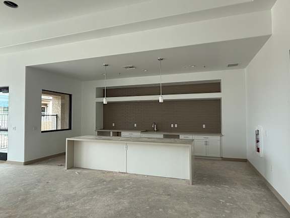 A large, empty room with a kitchen island in the middle.