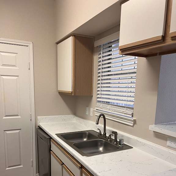 a kitchen with white cabinets and a sink and a window