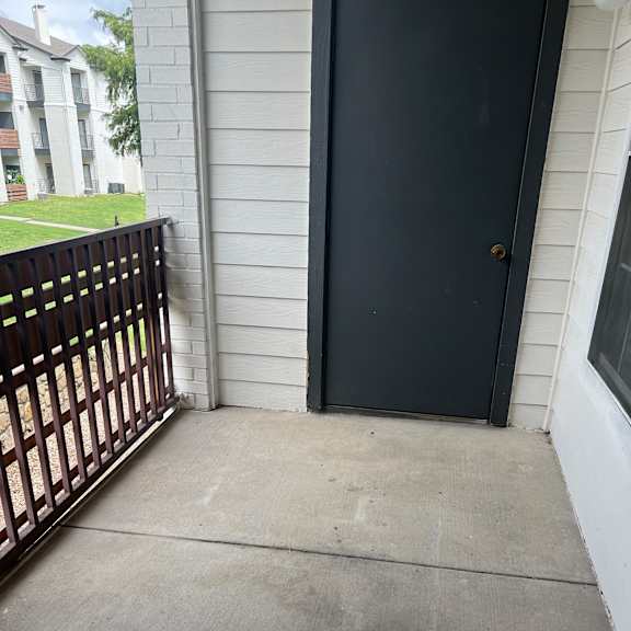 a balcony with a grate and a concrete wall and a window