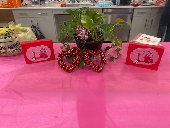 a table with a pink table cloth with a plant and two donuts on it at LIV at Boerne Hills an Active Senior Community 62+, Boerne, TX, 78006