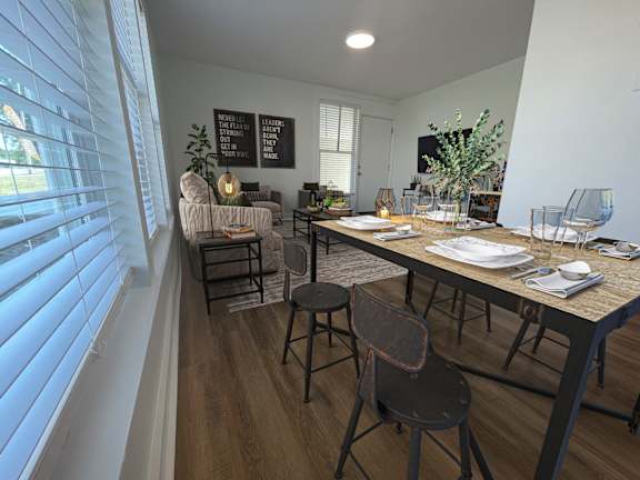A dining area with a table set for two and a couch with pillows.