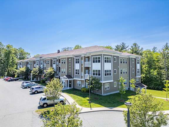 A large apartment complex with a parking lot in front.