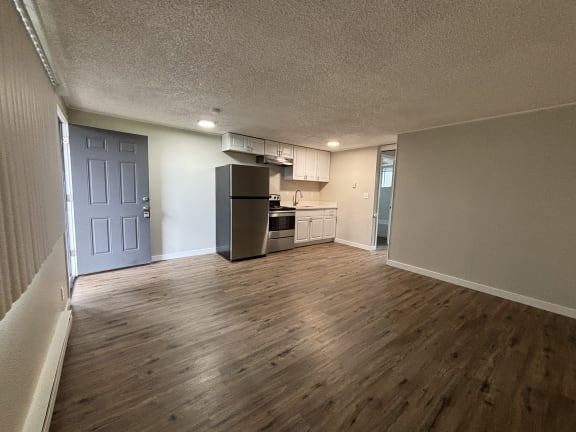 an empty living room and kitchen with a wood floor